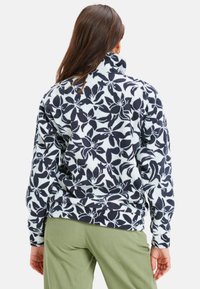 Fleece pullover met hoge kraag, voorzien van een marineblauw bloemmotief op een lichtblauwe achtergrond. Gebogen zoom, gestructureerde stof en geribde manchetten.