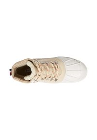 Sneaker alta beige con punta in gomma bianca, lacci marroni e fodera in pile. Caratterizzata da occhielli metallici e un'etichetta a strisce.