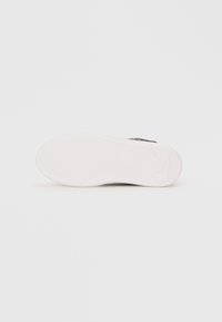 Shoe sole with a white rubber base featuring a textured pattern for grip, smooth edges, and a subtle logo imprint on the side.