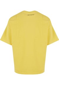 Yellow t-shirt with short sleeves, a relaxed fit, and a round neckline. Soft cotton material with minimal seams on the back.