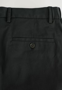 Schwarze Hose mit flacher Vorderseite, maßgeschneidertem Bund und einer Gesäßtasche mit einem einzelnen Knopfverschluss. Hergestellt aus strapazierfähigem Stoff mit glatter Oberfläche.