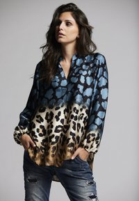 Long-sleeve blouse in blue and gold leopard print, featuring a collar, cinched cuffs, and a soft, glossy fabric with a relaxed fit.