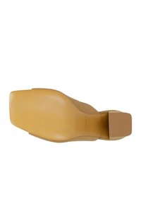 Suola di una scarpa in camoscio color cuoio con punta quadrata e tacco basso a blocco, mostrando una presa testurizzata e una finitura liscia.