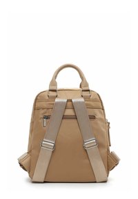 Zaino tan con una superficie liscia, tasca frontale con zip, spallacci imbottiti e una maniglia superiore per il trasporto. Design contemplativo.