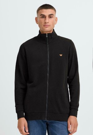 Zwarte zip-up sweatshirt met hoge kraag, ribbelmanchetten en -zoom. Bevat een klein bruin logopatch op de borst. Zachte stoftextuur.