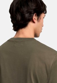 Olivengrøn t-shirt med rund hals. Blødt bomuldsstof, korte ærmer og en ensfarvet ryg med subtile syning detaljer.