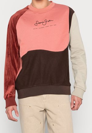 Sweatshirt à blocs de couleurs comprenant des panneaux roses, bordeaux, marron et gris. Fabriqué en tissu doux avec des poignets et un ourlet côtelés, et un logo imprimé.