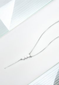 Sølv halskæde med tre geometriske diamantformede accenter langs en delikat kæde. Glat metaloverflade med poleret finish.