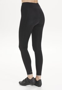 Black high-waisted leggings made from stretchy material, featuring reinforced seams and a smooth texture. Includes a subtle logo near the ankle.