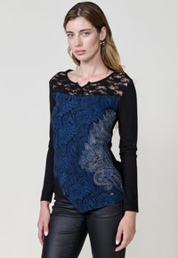 Haut à manches longues noir avec un col en dentelle et un motif paisley bleu sur le devant. Il présente une texture lisse et une coupe ajustée.