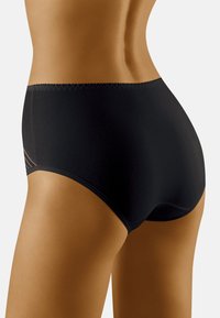 Hochschnittige schwarze Unterwäsche aus einem glatten, dehnbaren Material, mit einem subtilen Zickzackstich entlang des Bundes und seitlichen Akzenten.