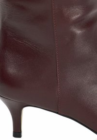 Bordeaux leren enkellaars met een spitse neus, strakke afwerking, minimale stiksels en een slanke hakontwerp.