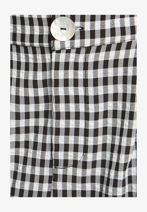 Tkanina s čierno-bielym károvaným vzorom s hladkým povrchom, ktorá obsahuje veľký strieborný gombík a prešité detail vrecka.