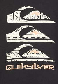 Camiseta negra con un diseño gráfico que presenta tres formas de montañas y olas blancas, acentuadas con detalles en melocotón claro y el texto "Quiksilver".