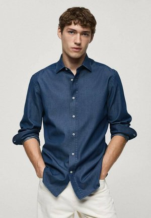 Tummansininen denim-paitapusero, jossa on pitkät käärityt hihat ja valkoiset napit, kapea malli, sileä pinta ja klassinen kaulustyyli.
