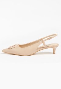 Chaussure à talon kitten en cuir beige, à bout pointu et avec une boucle décorative sur le dessus, sur fond blanc.