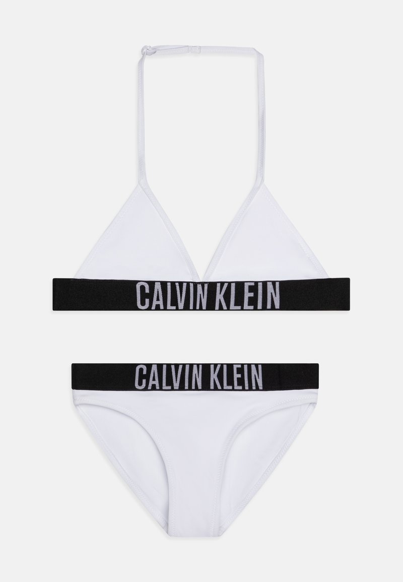 Fehér bikini szett, amely tartalmaz egy háromszög alakú bralette-t fekete Calvin Klein logóval díszített pánttal, és azonos logóval ellátott, hozzáillő alsót.