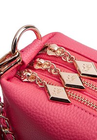 Różowa torebka skórzana o fakturze z złotymi elementami, podwójnymi zamkami i dekoracyjnymi uchwytami w kształcie diamentów. Posiada detal w postaci łańcuszka.
