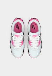 Nike Air sportbačiai turi baltą tinklinį viršų su juodais ir rožiniais akcentais, apvaliais raišteliais ir paminkštintu apvadu. Padas yra rožinis su ženklidara.