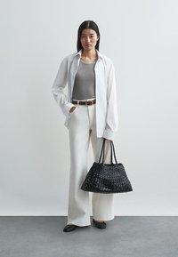 Balta marškinėlių palaidinė per pilką topą, kremiškos plataus kirpimo kelnės, juodas pintas rankinukas ir juodi butai. Glotnus audinys ir laisvas sijonas.