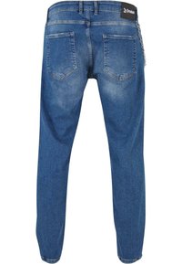 Vaqueros de denim en azul claro con un aspecto ligeramente deslavado, que cuentan con dos bolsillos traseros y un parche de logo en la cintura, finalizados con un acento de cadena.