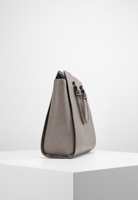 Šedá kožená kabelka se strukturovaným designem, obdélníkovým tvarem, dvojitými horními uchy a kovovými prvky. Hladký povrch s minimálními detaily hardwaru.