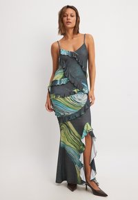 Maxi dress in dark gray with green and blue swirling patterns, featuring layered ruffles, adjustable spaghetti straps, and a thigh slit.