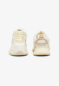 Baskets en matières crème et beige, avec des superpositions texturées, des lacets et un talon renforcé, accompagné d'un accent à motifs à l'arrière.