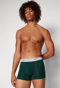 Green boxer briefs made of cotton, featuring a logoed white waistband. The fit is snug, with a brief-style design and smooth texture.