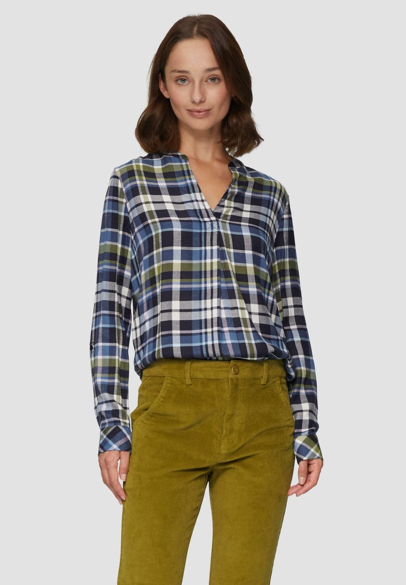 Kariertes Hemd in Marineblau, Grün und Weiß mit V-Ausschnitt und langen Ärmeln, kombiniert mit olivgrünen Cordhosen mit Knopfverschluss.