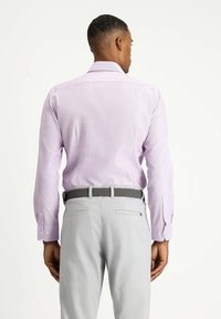 Camisa de manga larga de color púrpura claro con una textura sutil, que presenta puños abotonados. Combinada con pantalones grises y un cinturón trenzado.