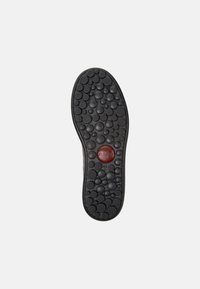 Suola di scarpa in gomma nera con motivi circolari, caratterizzata da accenti a bolle sollevate e un logo circolare rosso al centro contrassegnato con "44."