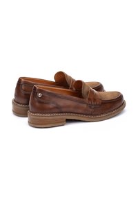 Mocasines de cuero marrón con puntera redondeada, diseño bicolor, detalles de costura en la parte frontal y suela de goma. Textura suave con acentos en contraste.