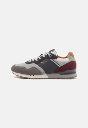 Zapatillas para hombre con parte superior de cuero y gamuza gris, detalles en negro, toques de burdeos y suela de goma texturizada. Diseño con cordones y cuello acolchado.