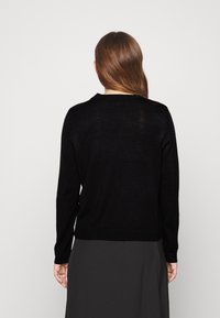 Czarny dzianinowy sweter z okrągłym dekoltem, długimi rękawami i prążkowanymi mankietami. Miękka w dotyku tekstura, dopasowany w talii, o minimalistycznym designie.