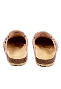 Sabots en feutre rose avec un intérieur en shearling beige doux, une semelle intermédiaire en liège brun, et une semelle extérieure en caoutchouc texturé ; accent en boucle en métal doré.