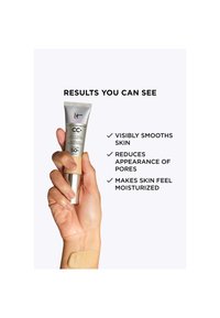 Main tenant un tube de crème CC+ IT Cosmetics avec un échantillon du produit sur le poignet et un texte énumérant les bienfaits lissants pour la peau, réducteurs de pores et hydratants.