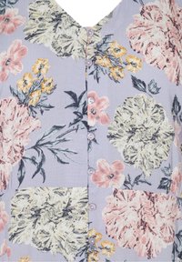 Blommig mönstrad skjorta med v-ringning, prydd med rosa, gula och vita blommor på en ljuslila bakgrund. Strukturerad tyg.