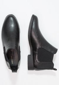 Bottines en cuir noir avec des panneaux latéraux élastiques, un bout arrondi et un petit talon empilé. Texture lisse avec un léger brillant.