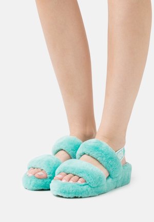 Turkusowe, puszyste klapki z dwoma szerokimi paskami, miękką fakturą i grubą podeszwą. Posiadają markowy pasek na pięcie dla lepszego dopasowania.