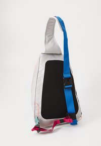 Saco transversal com um corpo de tecido cinza, painel lateral de malha preta, alça azul ajustável e detalhes em rosa. Apresenta um design assimétrico único.