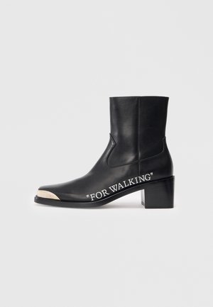 Black leather ankle boot with a square toe, mid-heel, and white printed text "FOR WALKING" on the side. Smooth texture and clean lines.