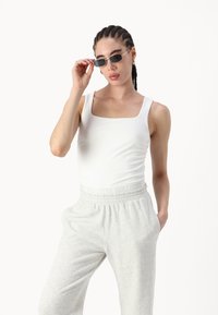 White square-neck tank top paired with gray sweatpants. The outfit features a comfortable fit and a soft, textured fabric.