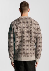 Πουλόβερ με στρογγυλή λαιμόκοψη και υφασμένο πλεκτό σχέδιο σε μπεζ και καφέ αποχρώσεις. Διαθέτει ριμπ μανσέτες και τελείωμα, με γεωμετρικό σχέδιο σε όλο το ύφασμα.