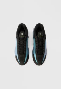 Czarne i akwamaryna sneakersy Nike Shox z oddychającą siateczkową cholewką, teksturowaną gumową podeszwą i wyraźnym systemem sznurowania. Na języku znajduje się logo.