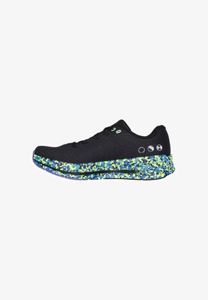 Baskets de sport noires avec une tige texturée, dotées d'une semelle colorée mouchetée de bleu et de vert. Deux accents circulaires sur le côté.