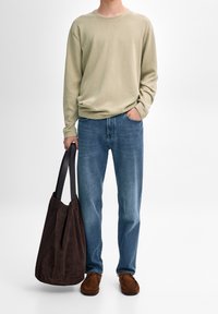 Camicia beige a maniche lunghe, jeans blu, scarpe in camoscio marrone e borsa a tracolla marrone scuro con manici neri. Abbigliamento semplice e comodo.