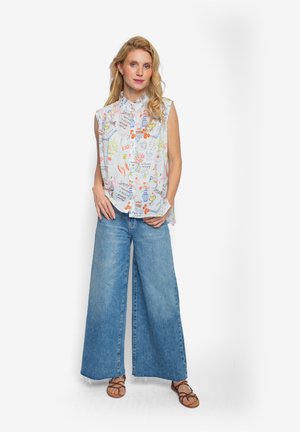 Jasnoniebieska bluzka bez rękawów z kolorowymi wzorami, zestawiona z szerokimi jasnoniebieskimi jeansami i brązowymi sandałami na paski, na białym tle.