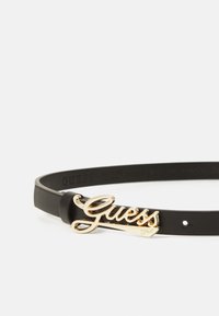 Ceinture en cuir noir avec une boucle en métal doré brillant portant le logo "Guess". La ceinture a une texture lisse et des trous réglables pour s'adapter à la taille.