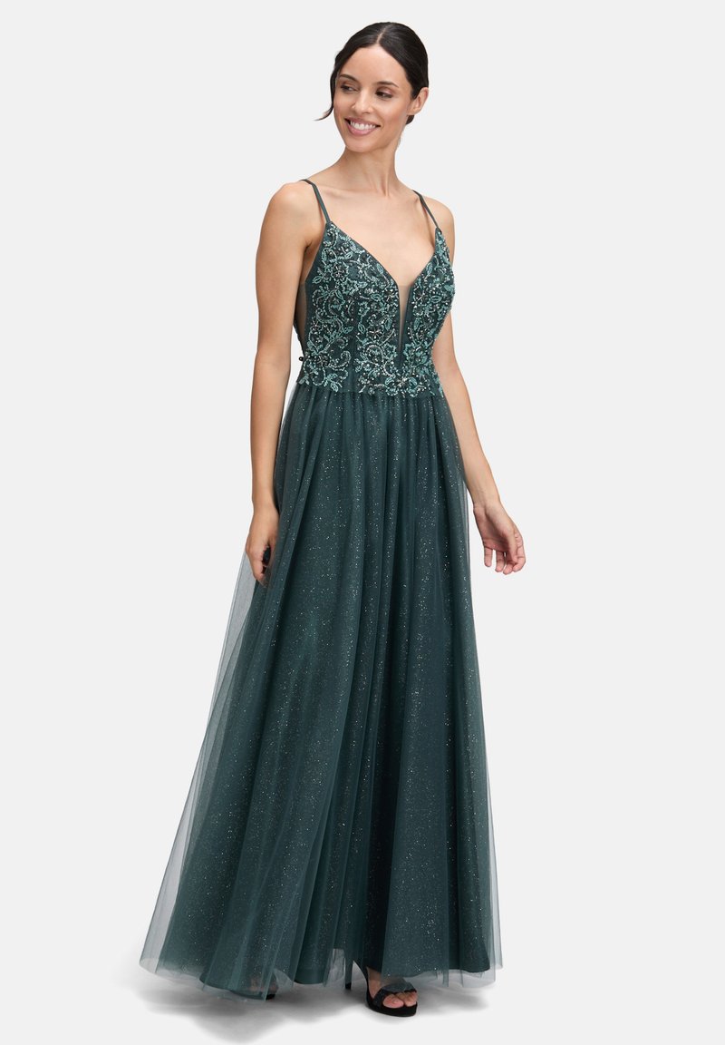 Długa, ciemnozielona suknia z dopasowaną górą, zdobiona misterną haftą, z głębokim dekoltem w kształcie litery V oraz warstwową spódnicą z tiulu, dającą efekt połysku.